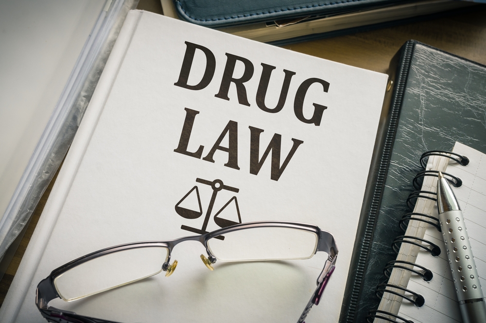 A photo of a n eye glasses above on a book of drugs and laws