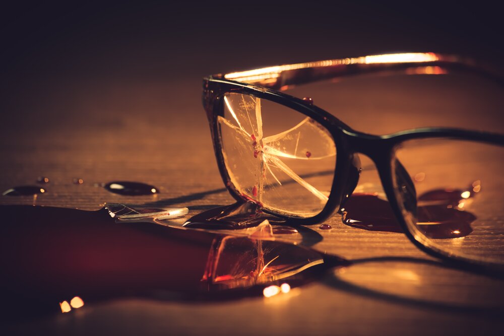 A broken eye glasses with a blood on it in the ground indicating of something bad happened