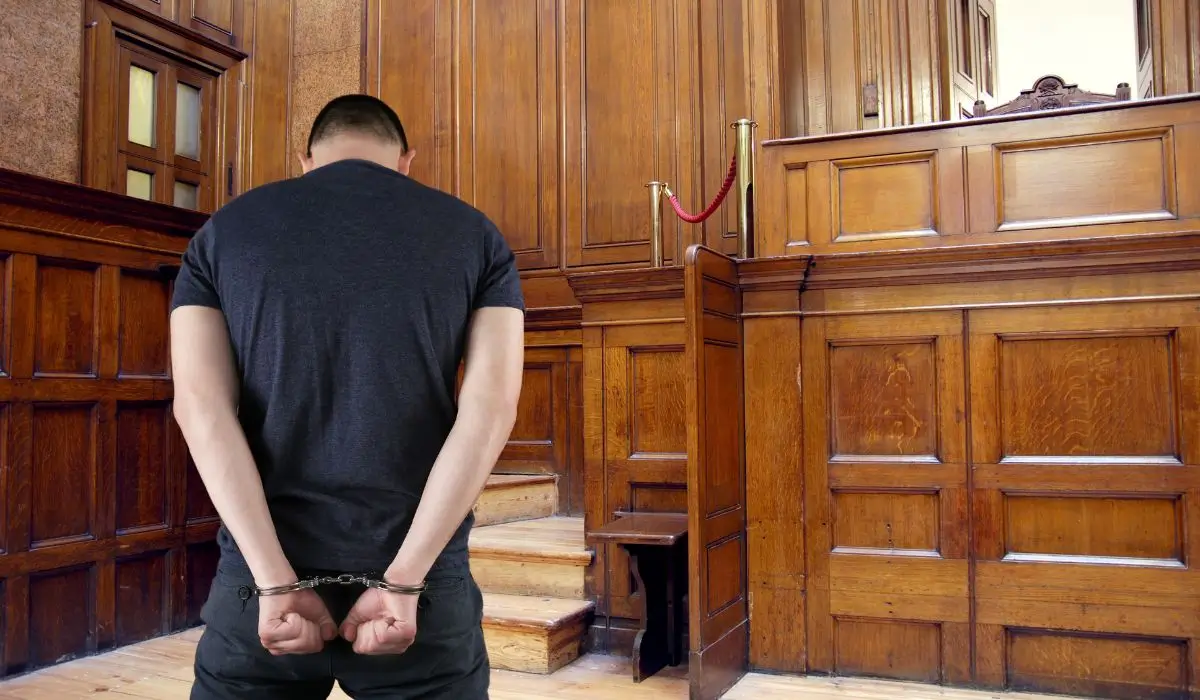 Man in handcuffs inside courtroom facing judge after being arrested for alleged violent crime in Illinois.