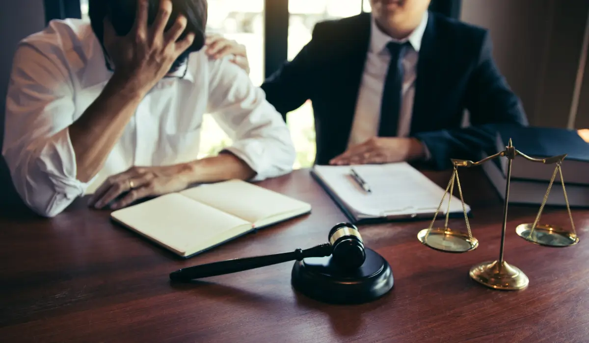 A worried man sits with his head in hand as a criminal defense attorney offers comfort and guidance during a murder defense consultation in Illinois.