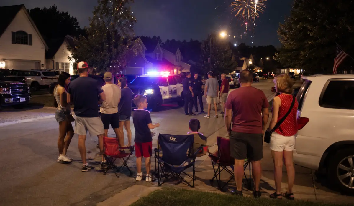 Neighborhood Fourth of July celebration with fireworks overhead and police officers responding to an incident, illustrating Independence Day Arrests and holiday-related criminal investigations in Illinois.